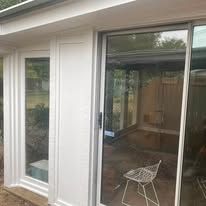 White sliding glass doors and windows with a small white chair outside a house.