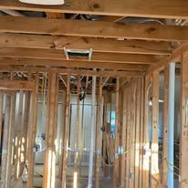 Interior of a house under construction with exposed wooden framing and ceiling joists