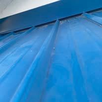 Close-up of a blue metal roof with overlapping panels and diagonal ridges