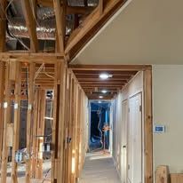 Unfinished hallway with exposed wooden framing and ceiling beams in a house under construction