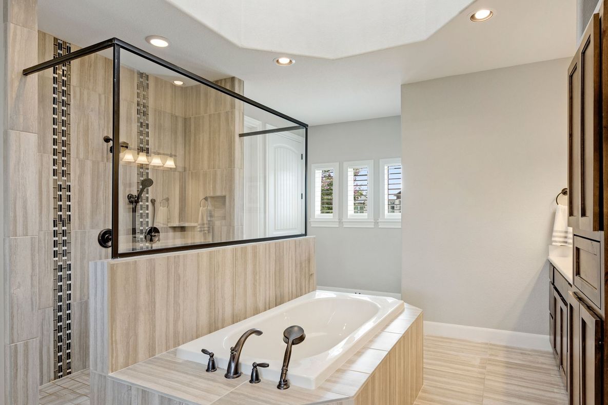 Modern bathroom with a freestanding tub, glass shower, and light wood cabinetry