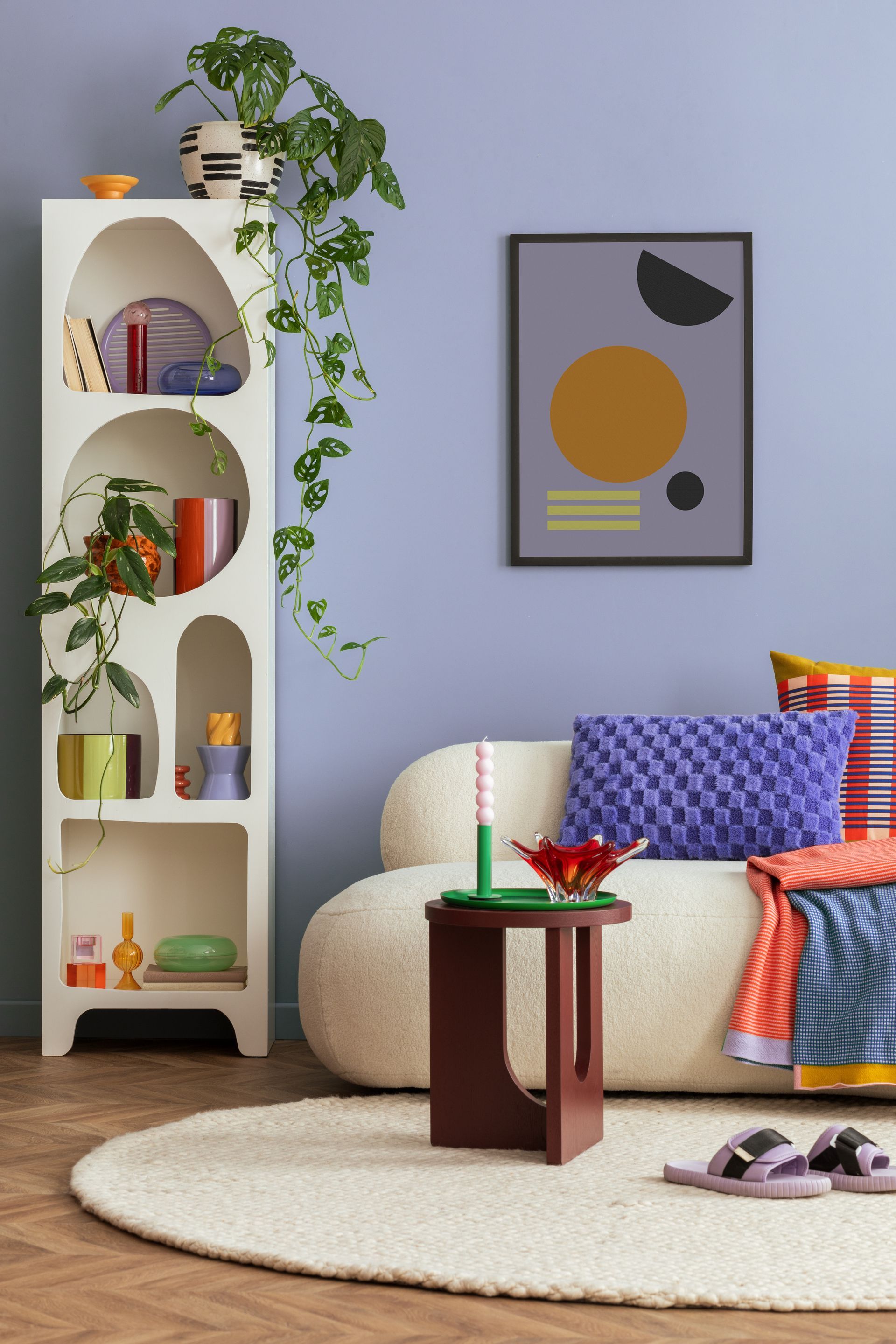 Cozy living room with white sofa, patterned pillows, arched shelf, wall art, rug, and small wooden table