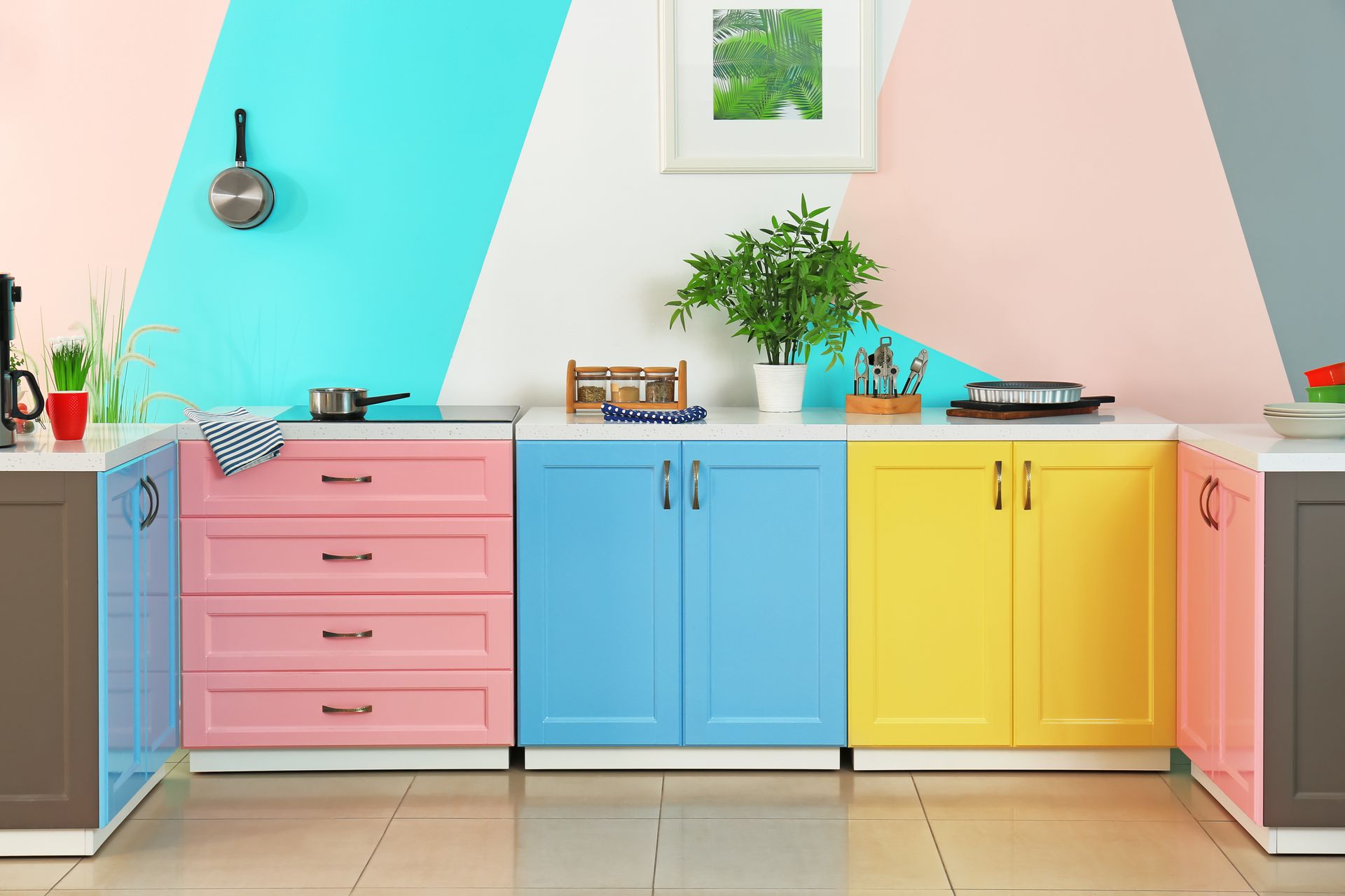 Colorful modern kitchen with pastel pink, blue, and yellow cabinets and a potted plant on the counter