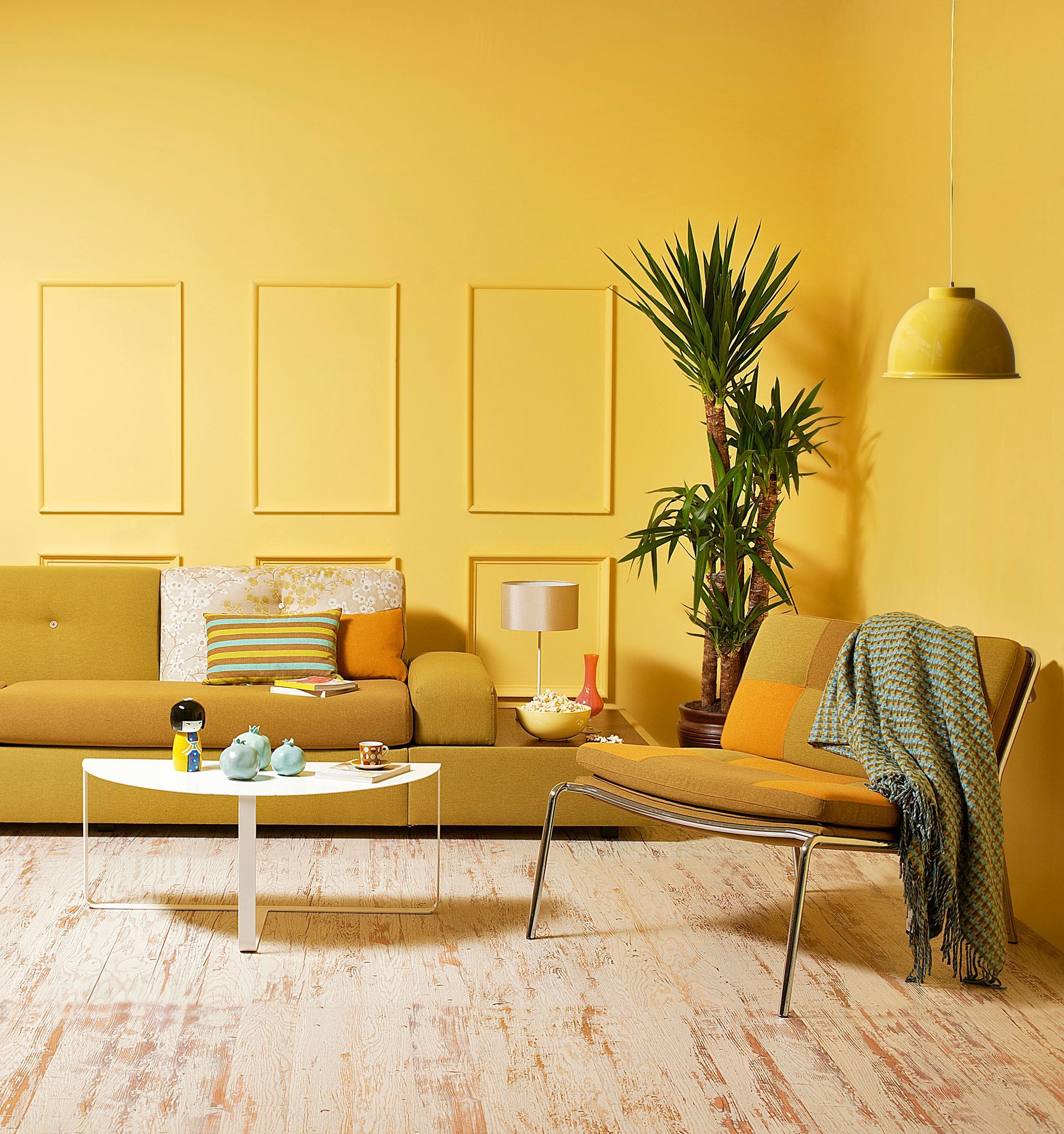 Yellow living room with beige sofa, coffee table, plant, hanging lamp, and patterned chair.