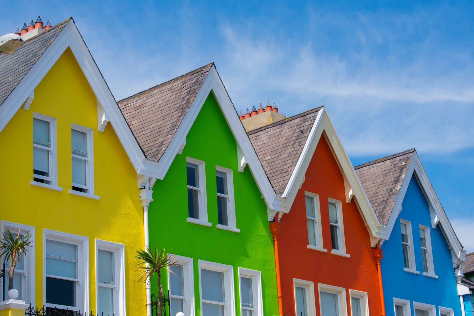 Colorful row of houses with bright yellow, green, orange, and blue facades under a blue sky