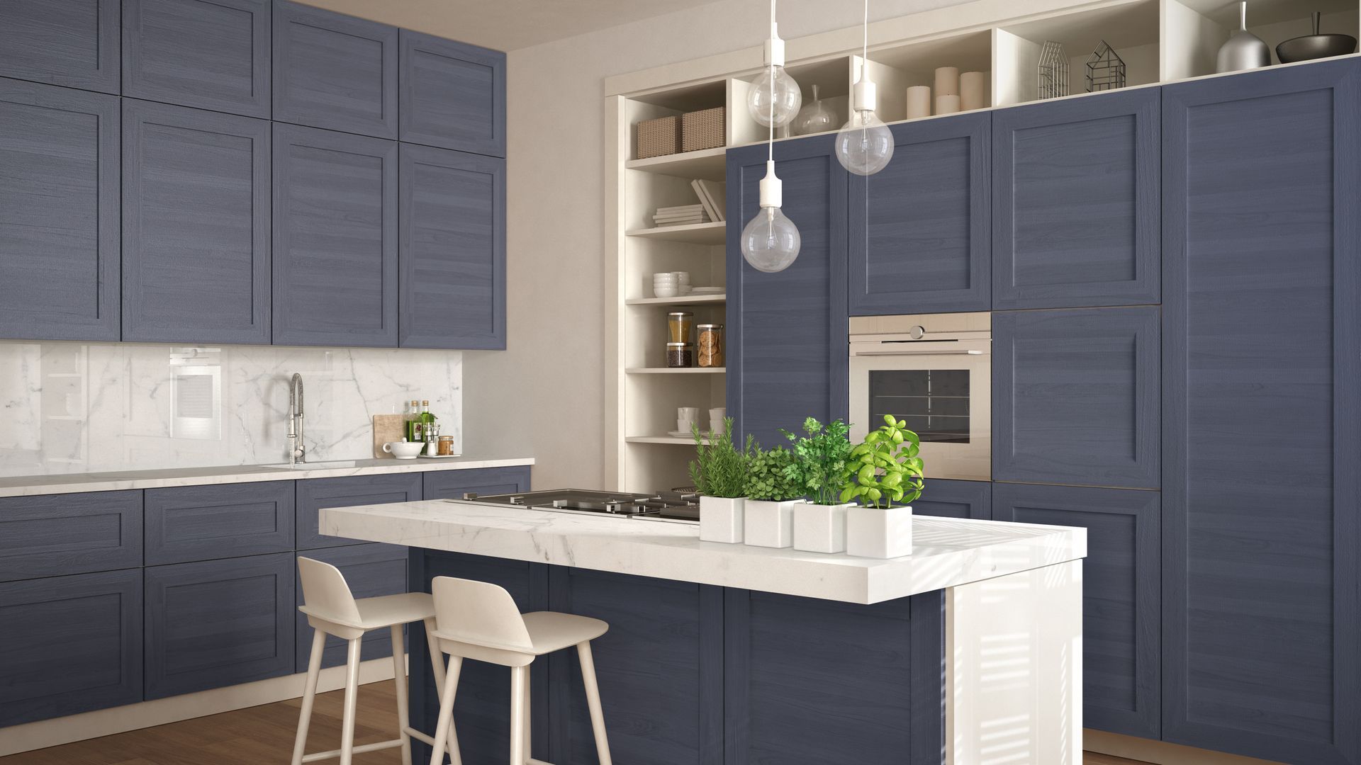 Modern kitchen with navy cabinets, white island, and pendant lights, featuring a built-in oven and potted herbs.