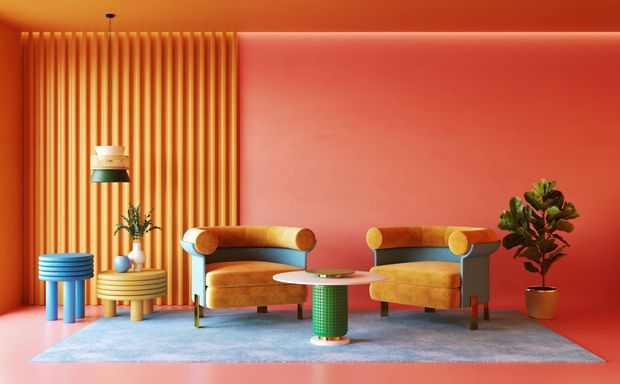 Stylish living room with orange walls, two mustard chairs, side tables, plants, and a blue rug