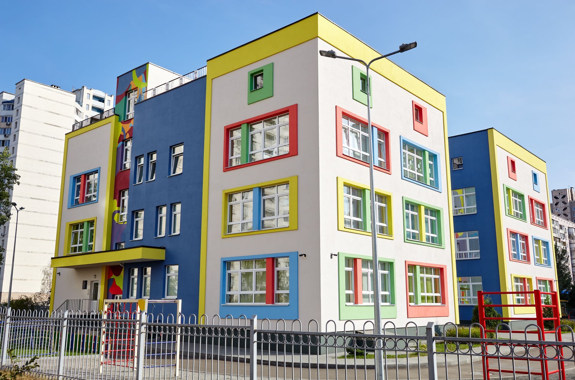 Colorful modern apartment building with bright window frames and a fenced courtyard