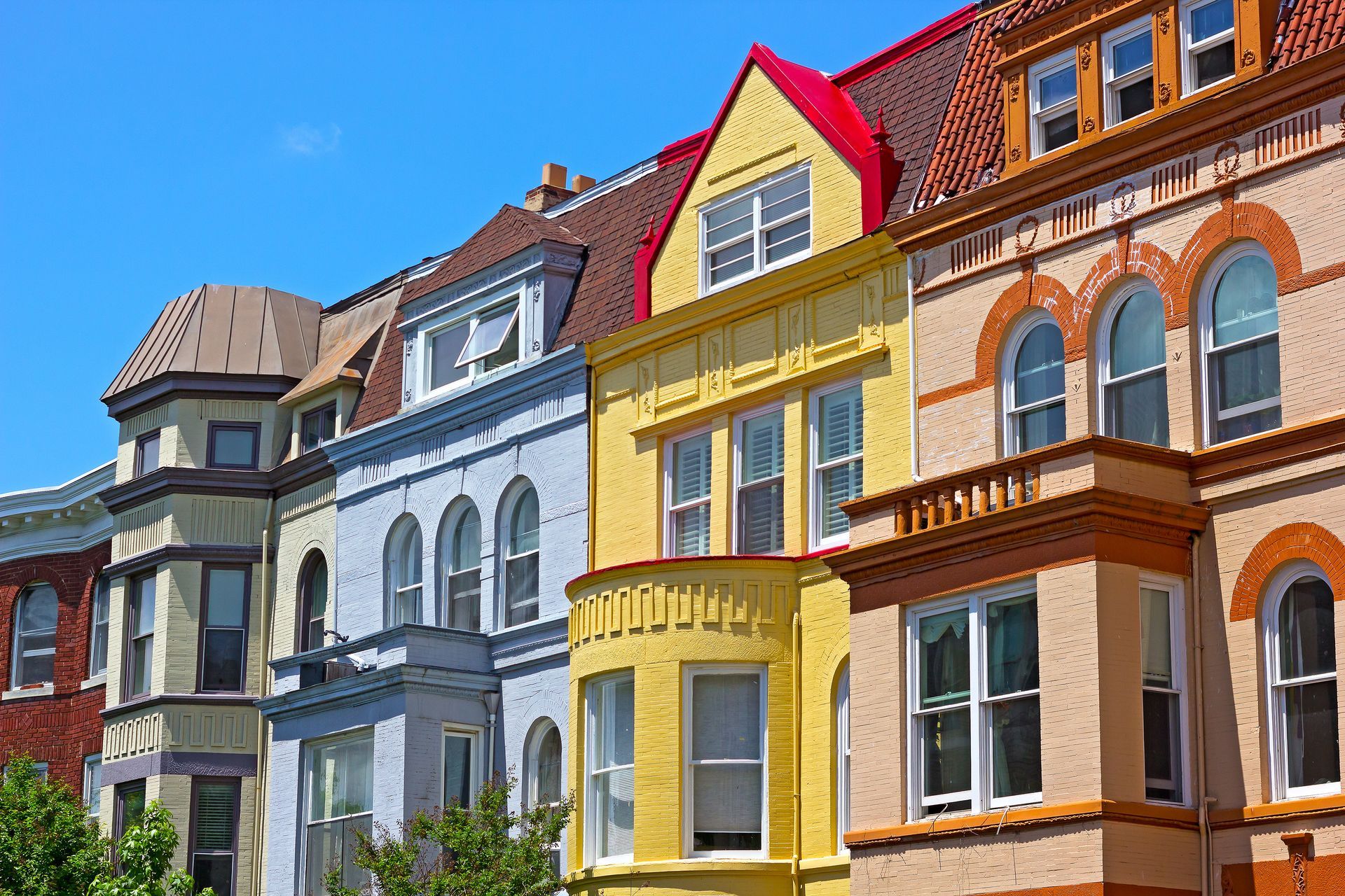 Colorful row of Victorian-style townhouses with ornate facades under a bright blue sky