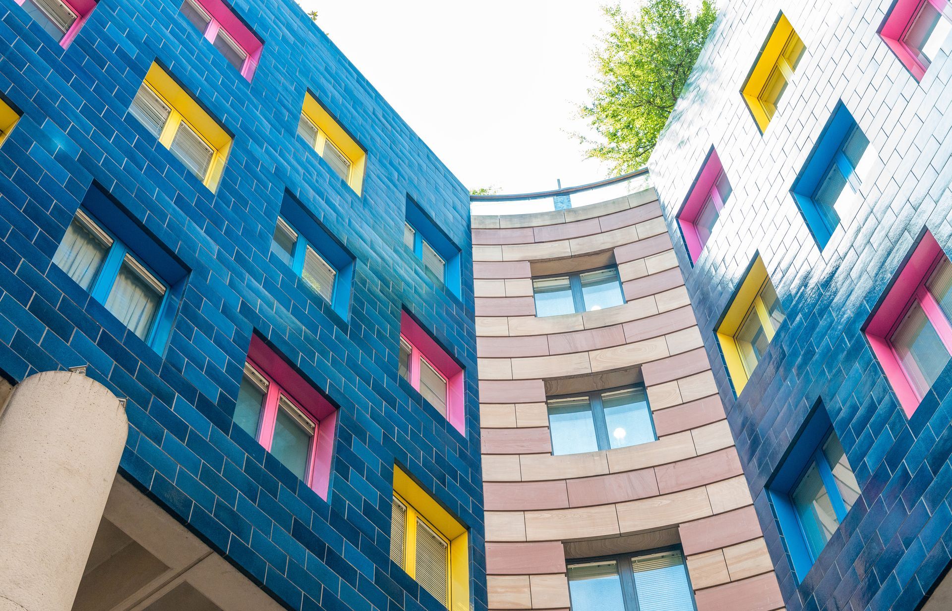 Colorful modern apartment buildings with blue, pink, and beige facades viewed from below