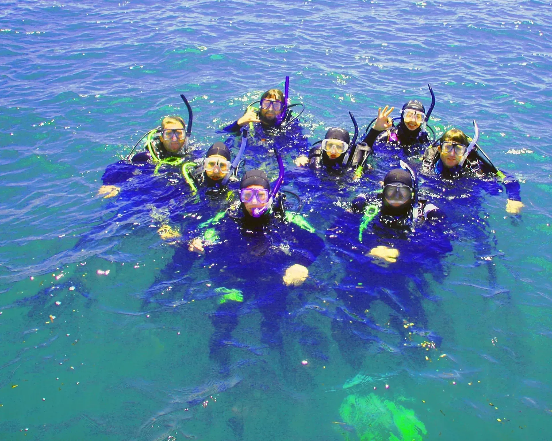 A group of snorkelers in blue water, floating together with masks and snorkels.