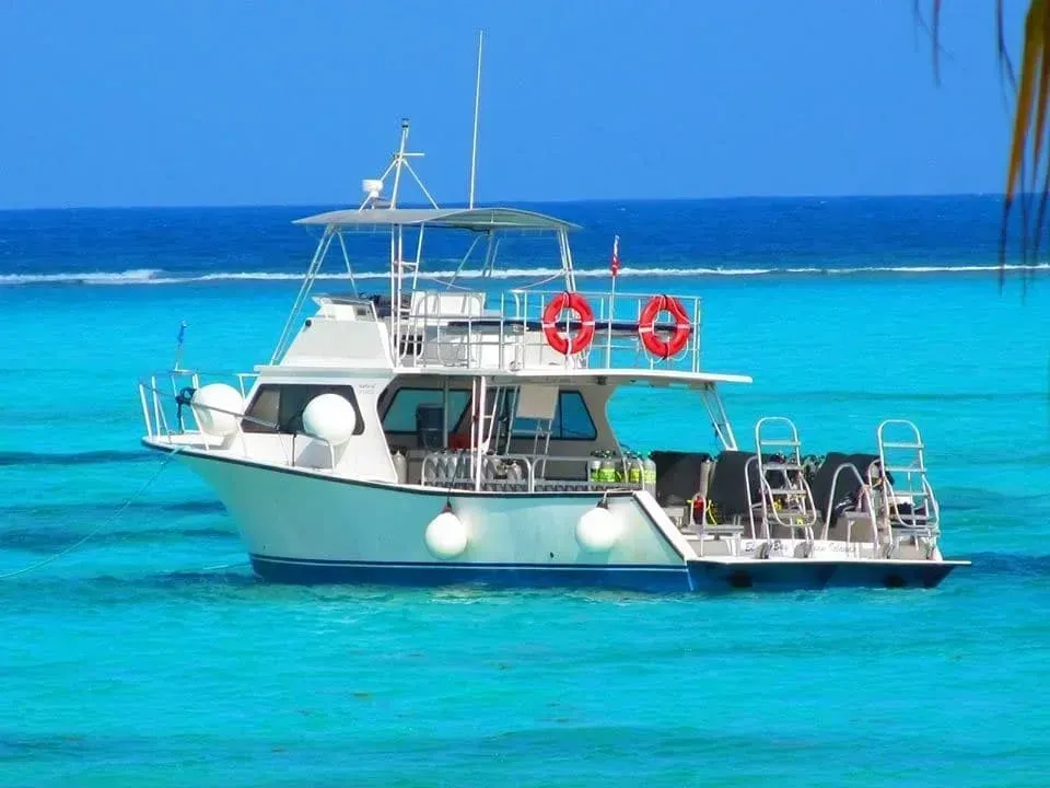 White boat on bright turquoise water with calm blue sea in the background
