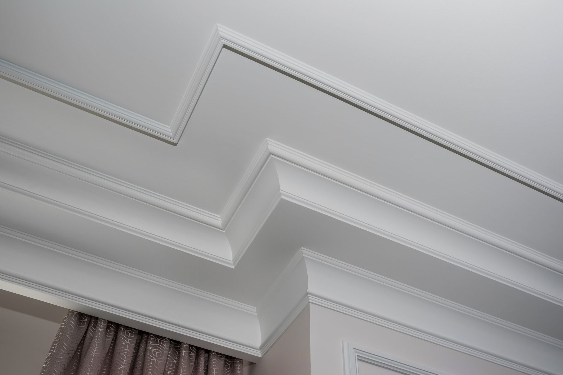 White decorative crown molding on a ceiling, creating an architectural design.