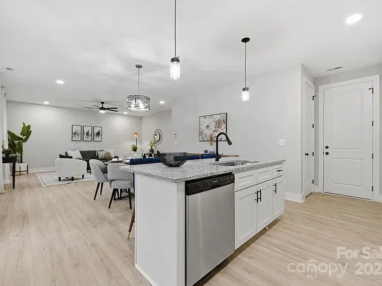 Bright open-concept kitchen and living room with white cabinets, island, and light wood floors