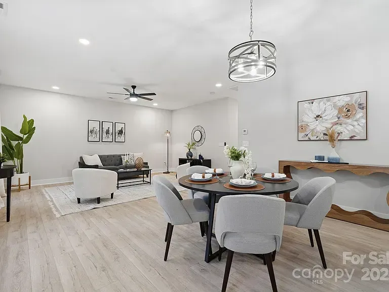 Bright open-concept living and dining room with gray furniture, white walls, wood floors, and modern decor