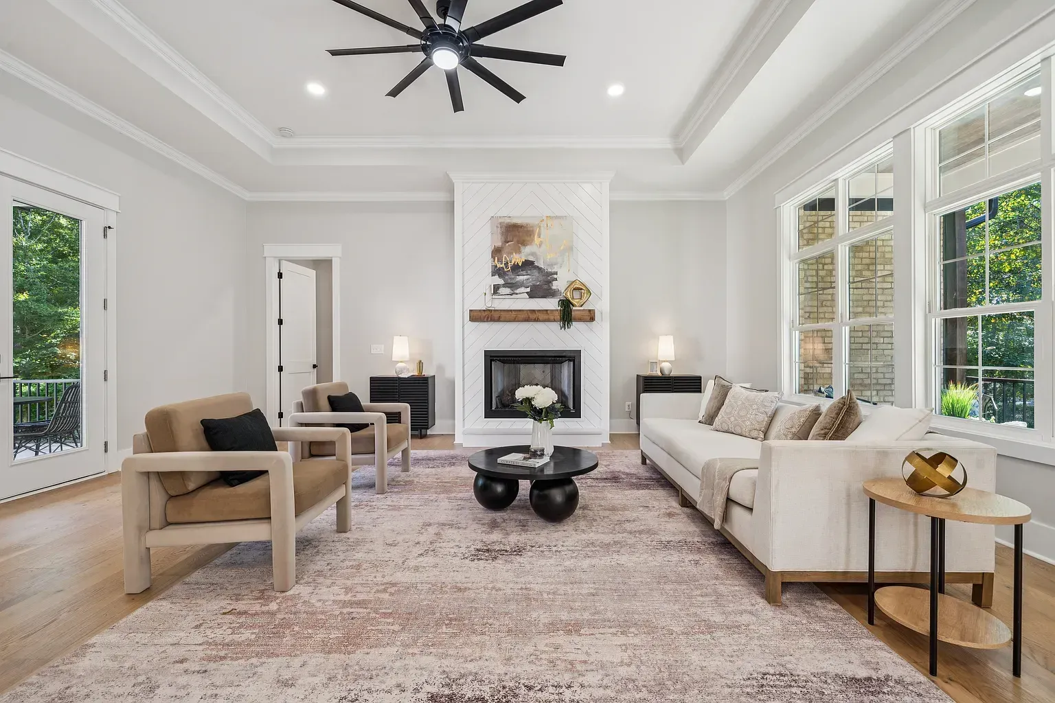 Bright modern living room with white walls, fireplace, large windows, and beige seating around a coffee table