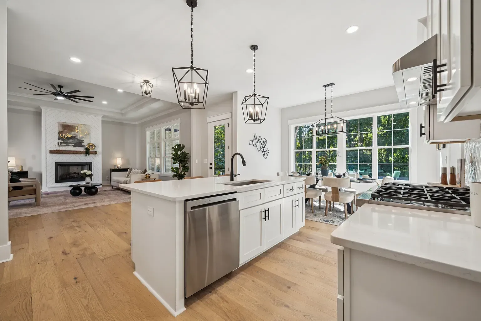 Bright modern kitchen with white island, stainless appliances, and large windows overlooking a yard