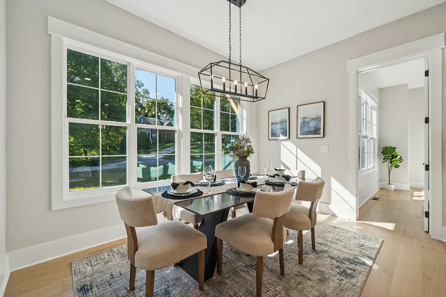 Bright dining room with a glass table, upholstered chairs, large windows, and a chandelier.