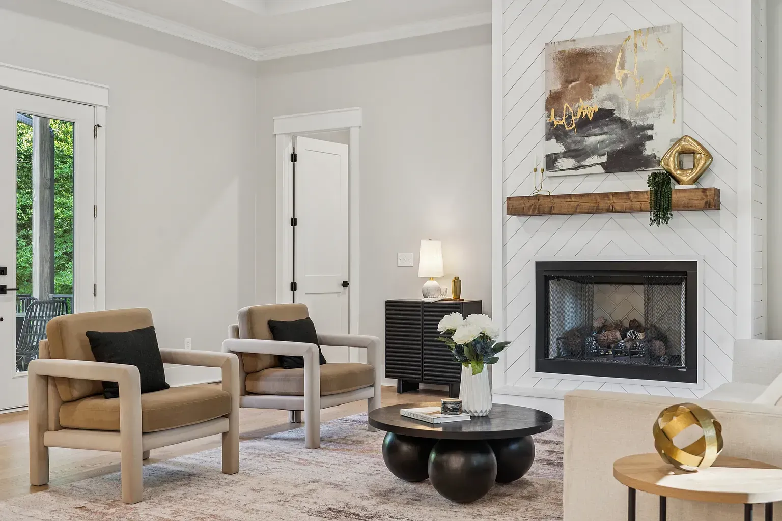 Bright living room with two chairs, fireplace, mirror, and neutral decor
