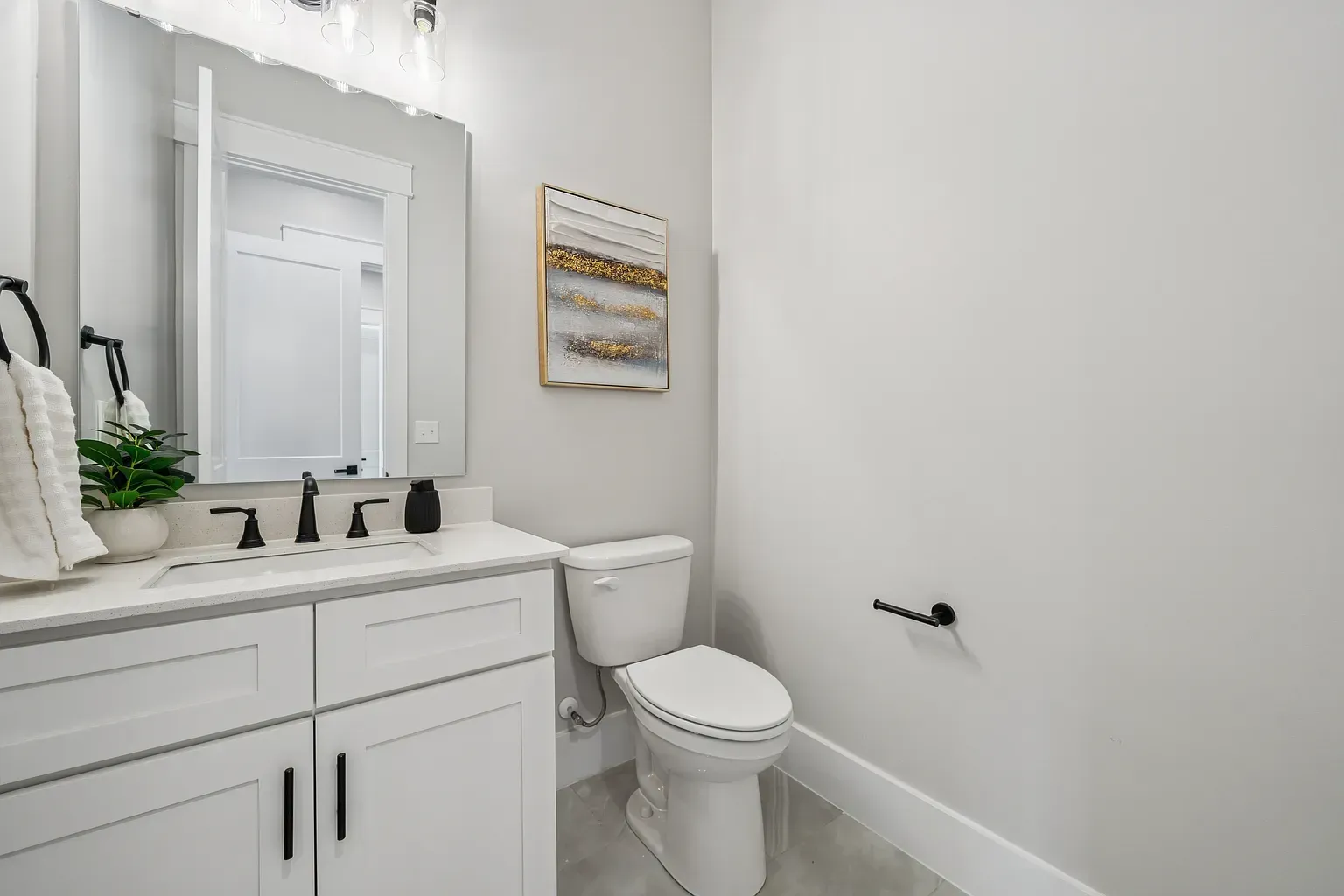 Bright white bathroom with vanity, mirror, toilet, and framed wall art