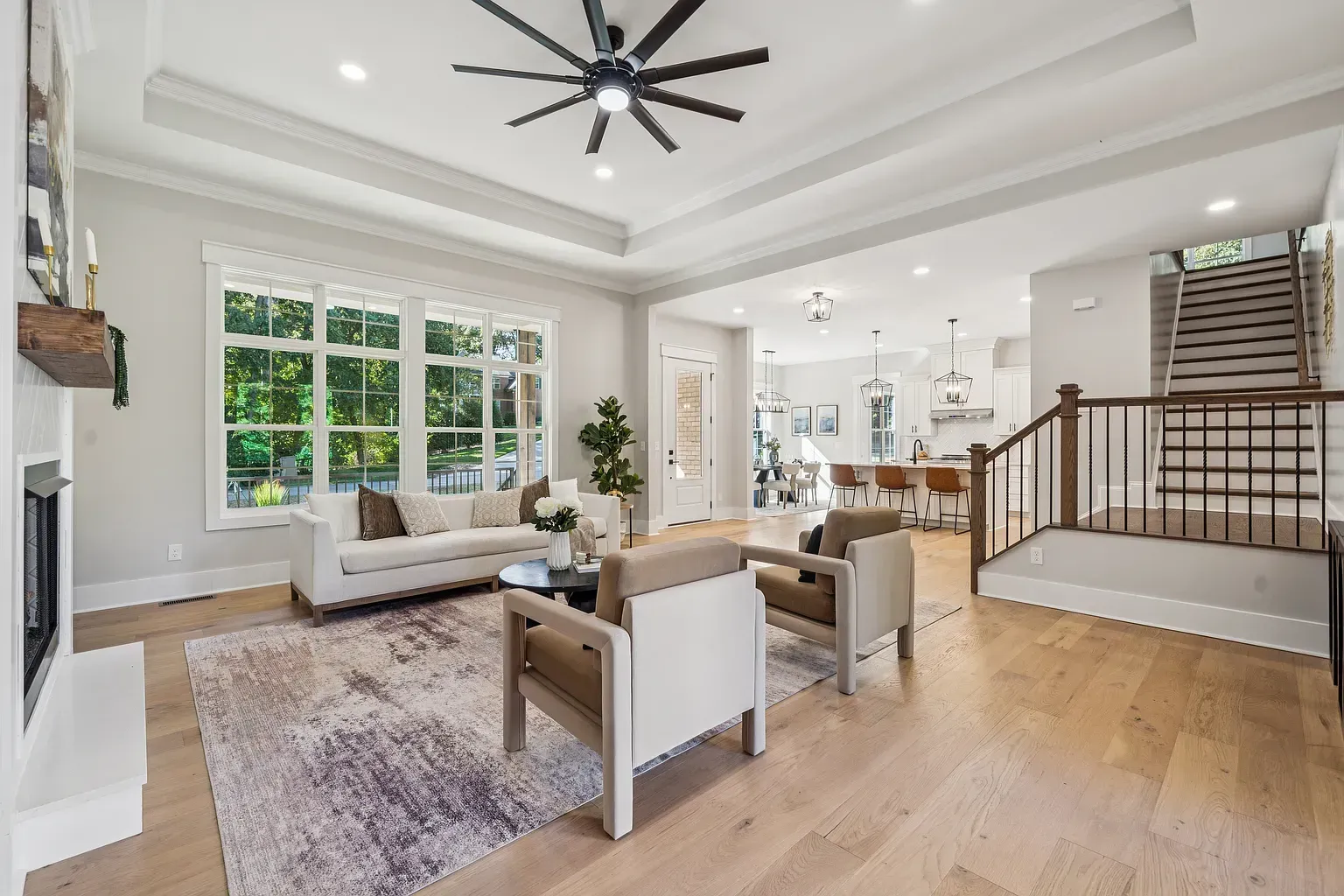 Bright, open living room with large windows, white walls, wood floors, and modern neutral furniture