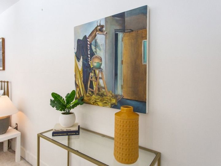 Modern room with wall art, brass console, yellow vase, potted plant, and table lamp