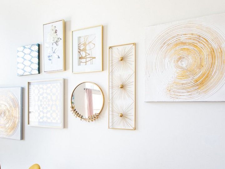Minimal gold and white abstract wall art and mirrors arranged in a gallery-style display on a white wall