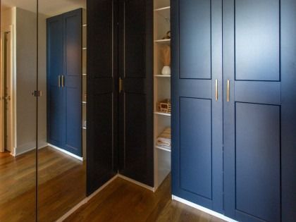 Blue built-in wardrobe with mirrored doors in a room with hardwood floors and beige walls