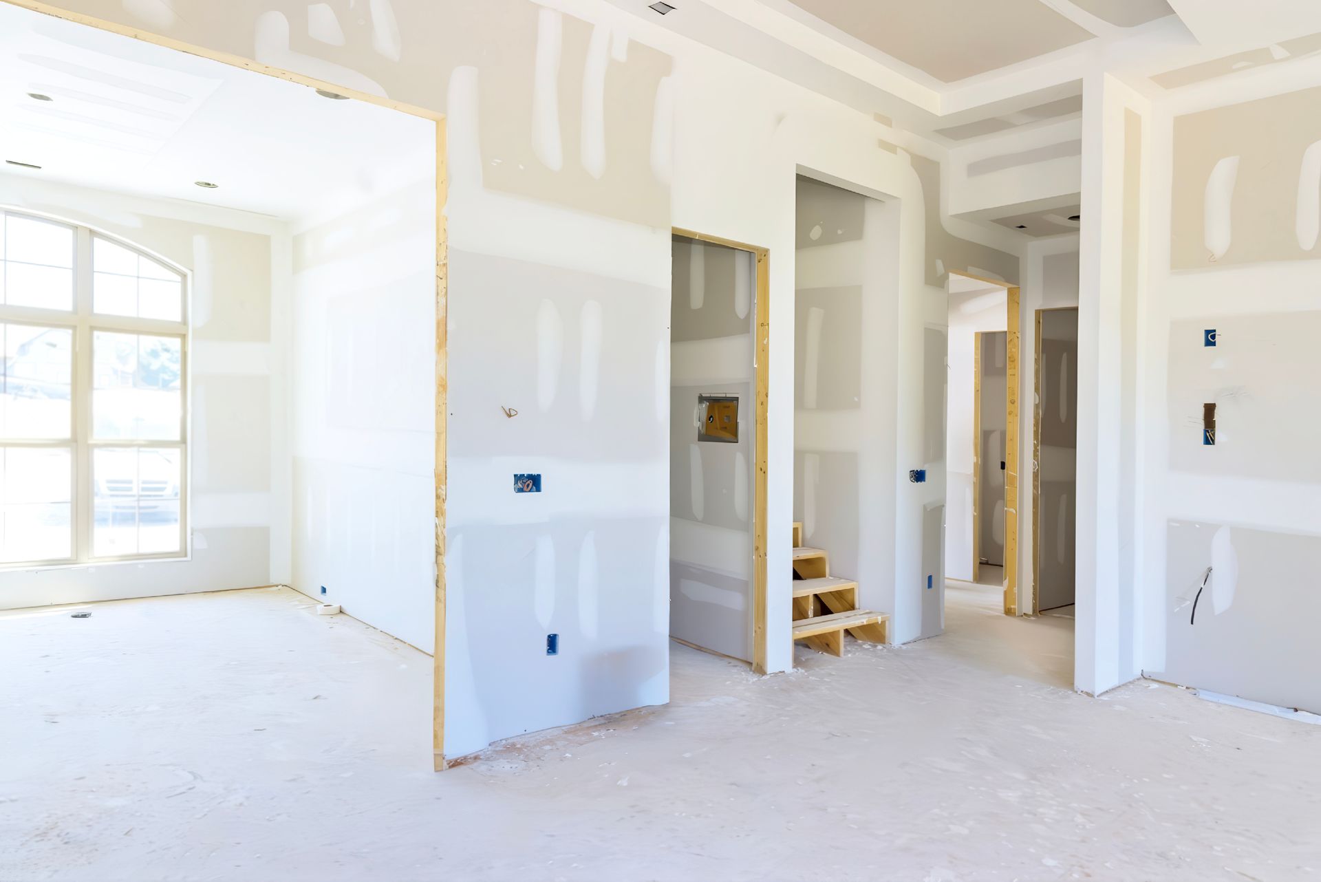 An empty room in a house under construction with drywall on the walls.
