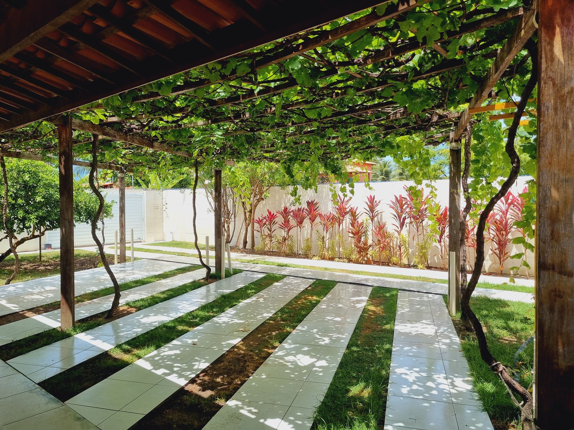 Um pátio com uma pérgola de madeira e um piso listrado Pousada Cantinho da Melão