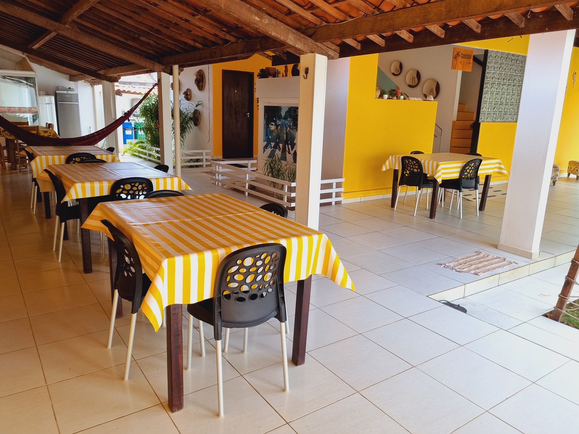 Um restaurante com mesas e cadeiras amarelas sob um teto Pousada Cantinho da Melão