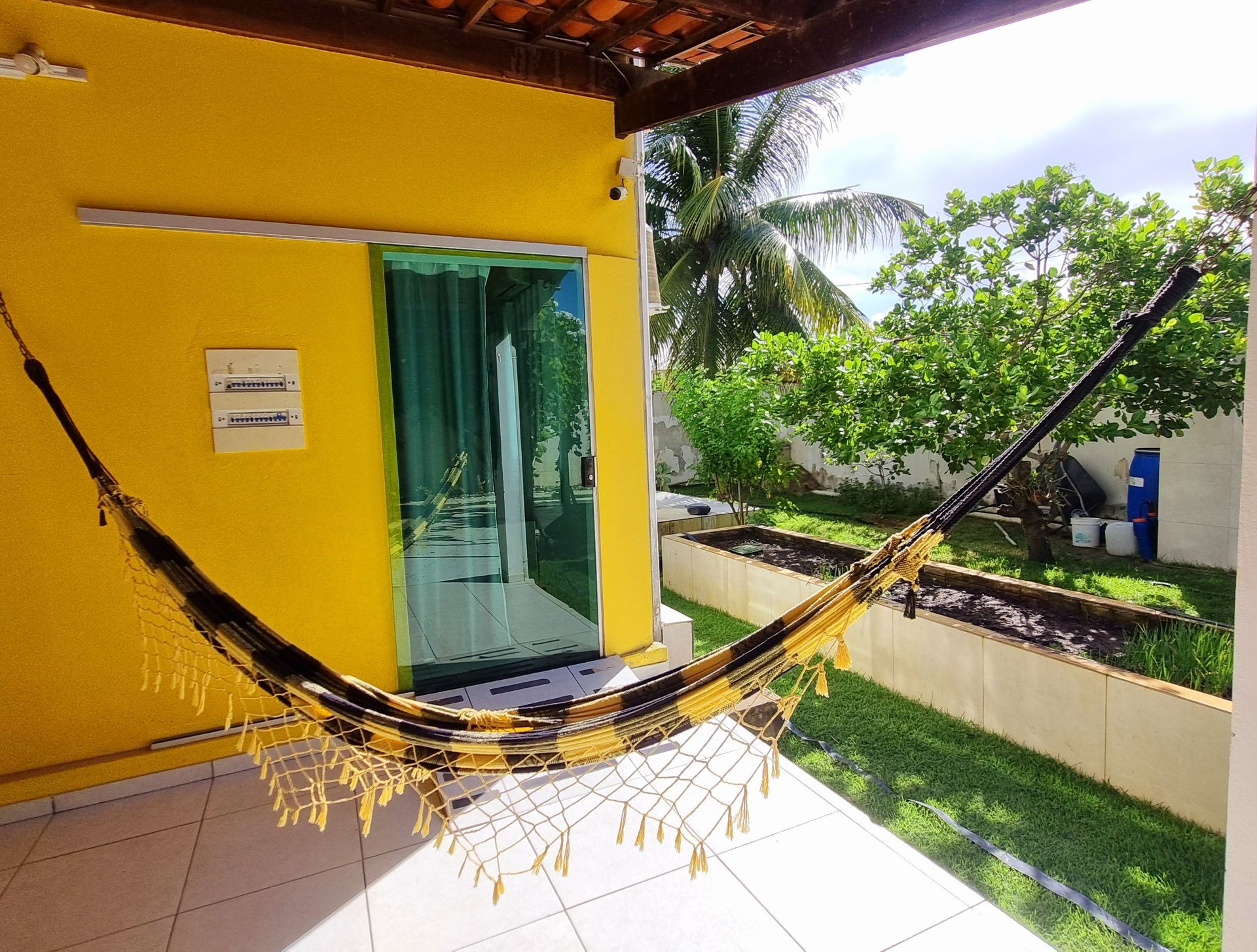 Um prédio amarelo com uma rede na frente Pousada Cantinho da Melão