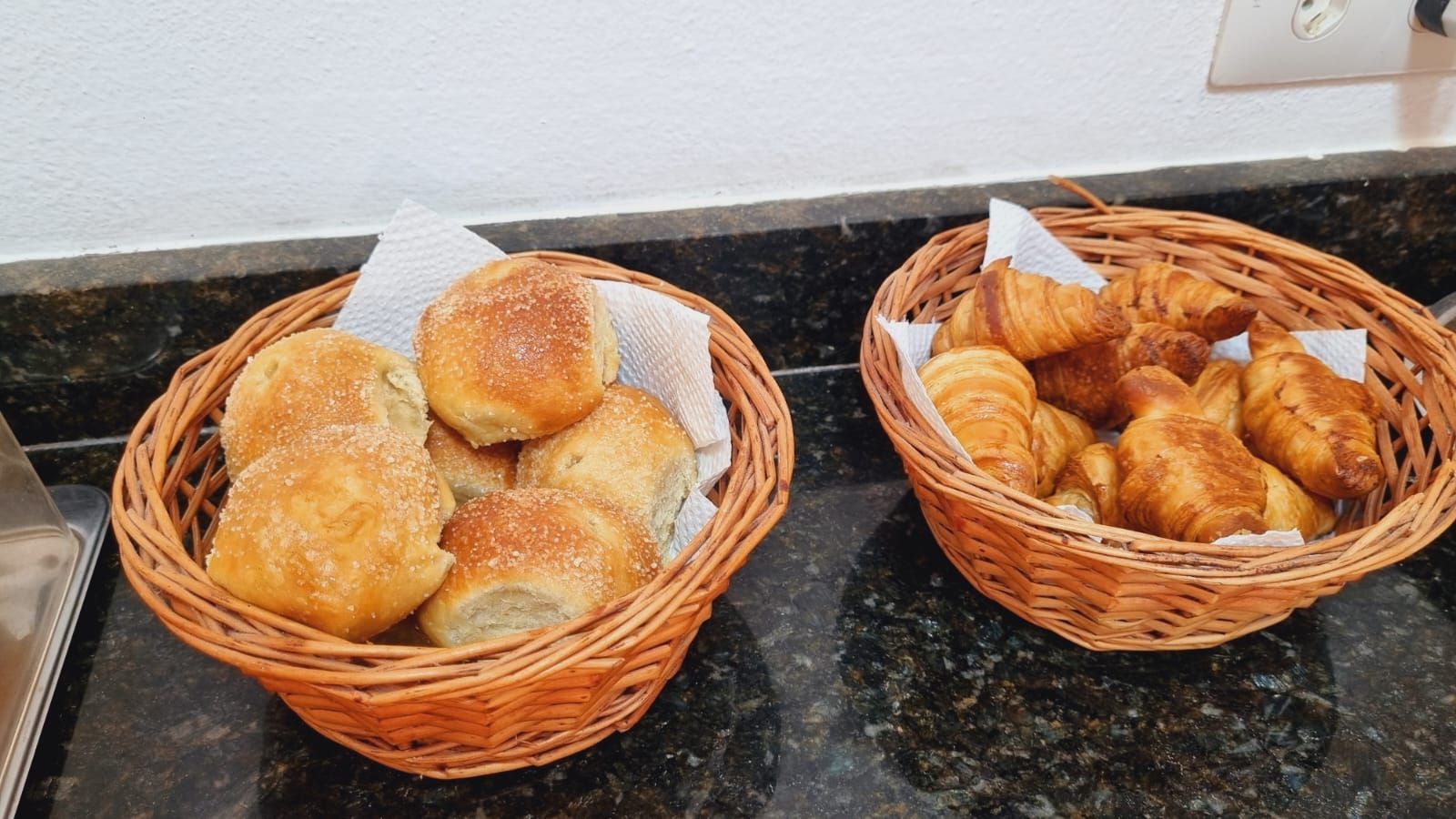 Duas cestas de pães e croissants estão sobre um balcão. Cantinho da Melão