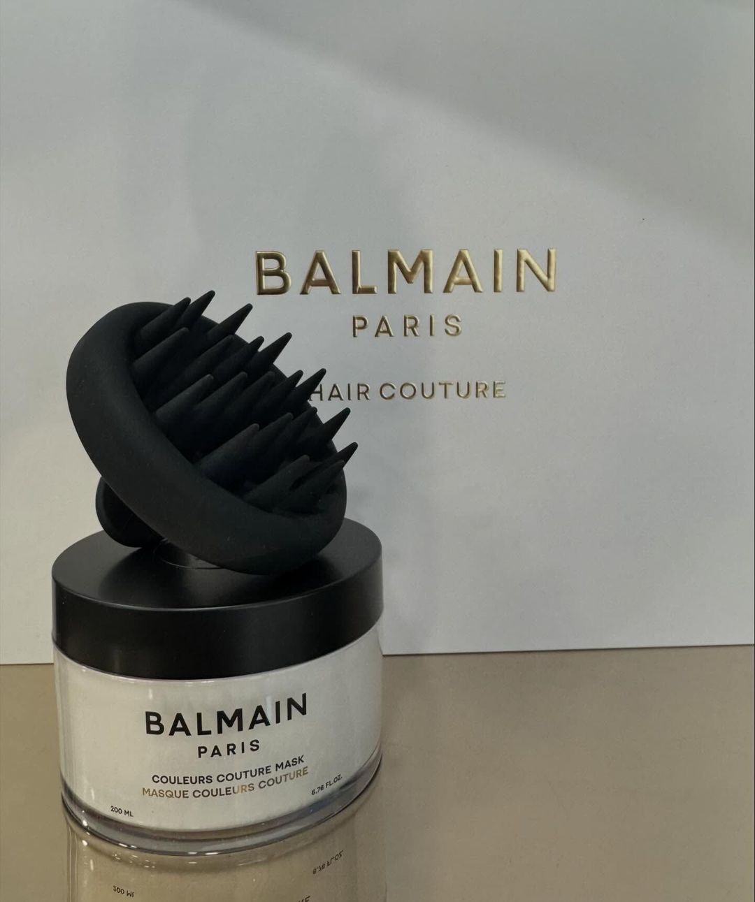 Una spazzola per capelli Balmain è appoggiata sopra un barattolo di Balmain Hair Couture