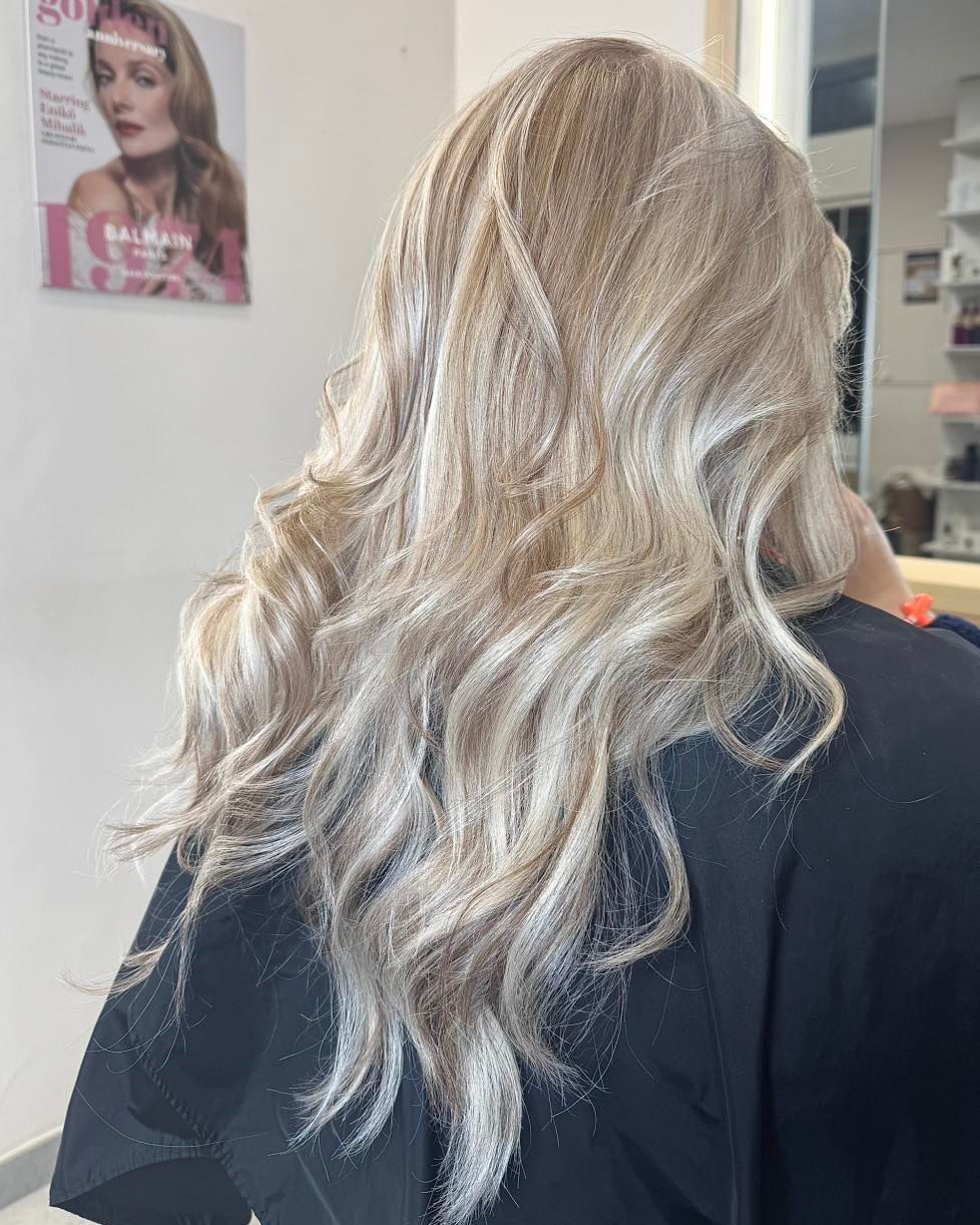 Una donna con lunghi capelli biondi è seduta su una sedia in un salone.