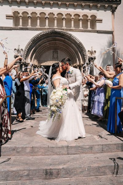 Couple kissing in a church aisle during a wedding ceremony, with guests standing and clapping.
