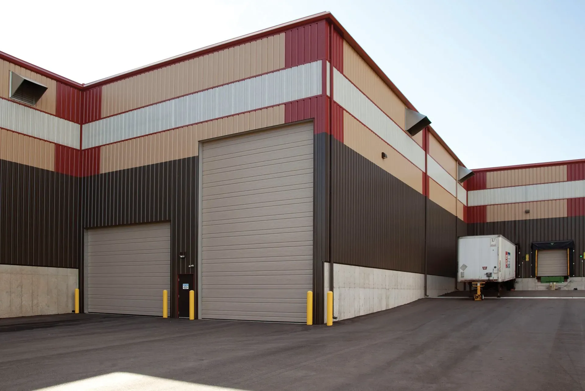 .Large Garage Door Commercial Loading dock of a warehouse building with brown and red siding; a semi-truck trailer