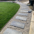 Hands rolling out a strip of grass sod on a lawn outdoors.