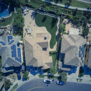 Aerial view of suburban houses with solar panels and a backyard pool