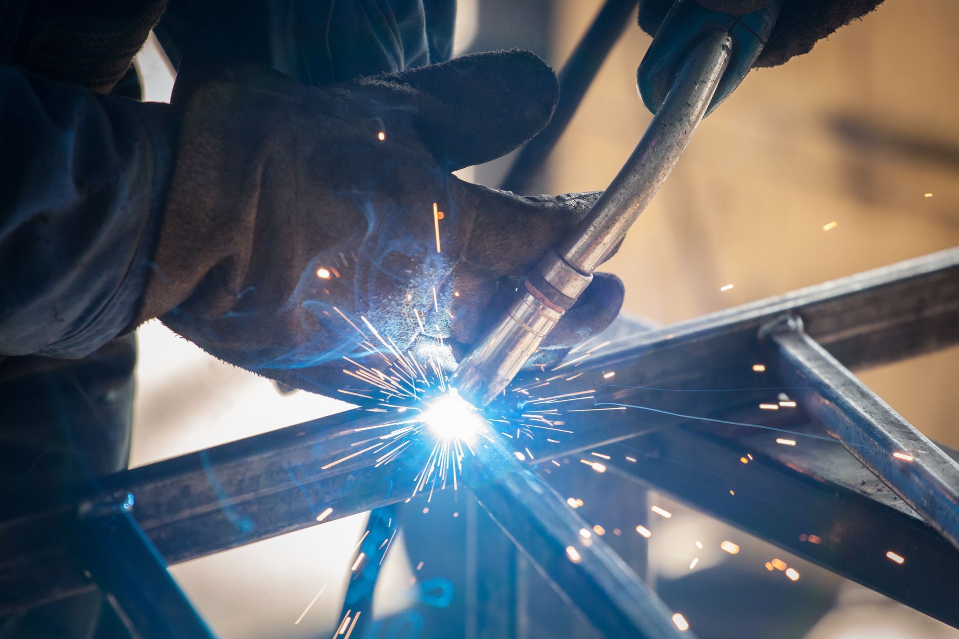 Close-up of welding torch joining metal frame with bright sparks flying.