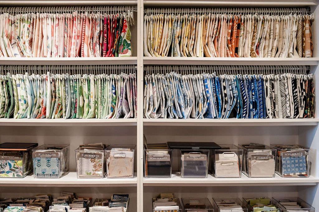 Shelves filled with fabric swatches, arranged by color, and fabric samples in containers.