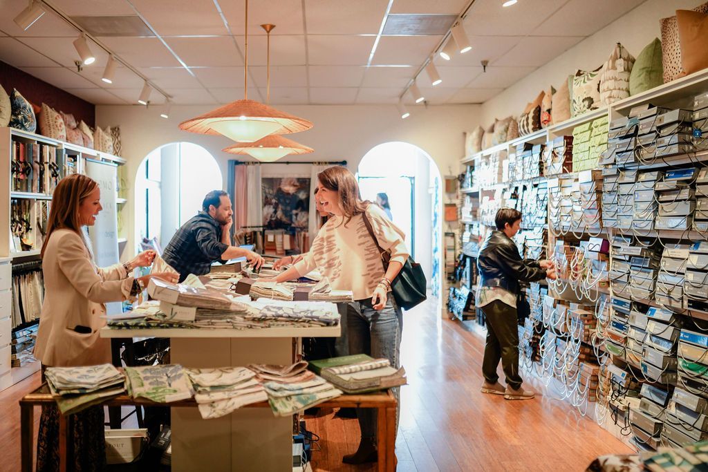 People browsing merchandise inside a brightly lit retail store. Products line shelves and display tables.