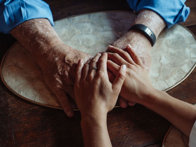 Two hands clasping a larger hand over a round table