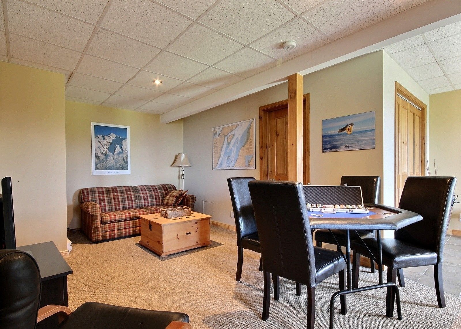 Cozy finished basement with a sofa, wooden table, chairs, and artwork.