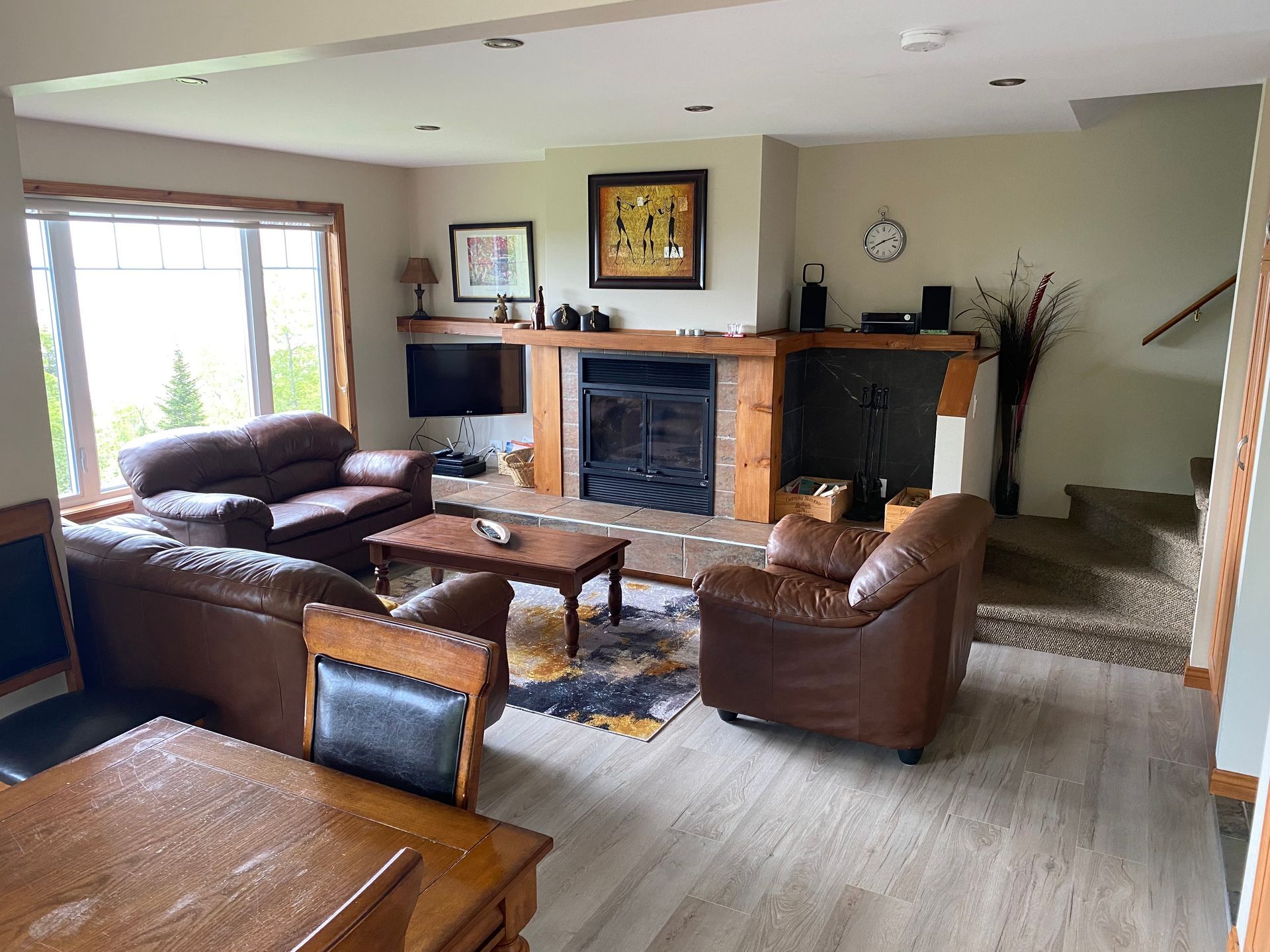 Living room with leather furniture, fireplace, and large windows.