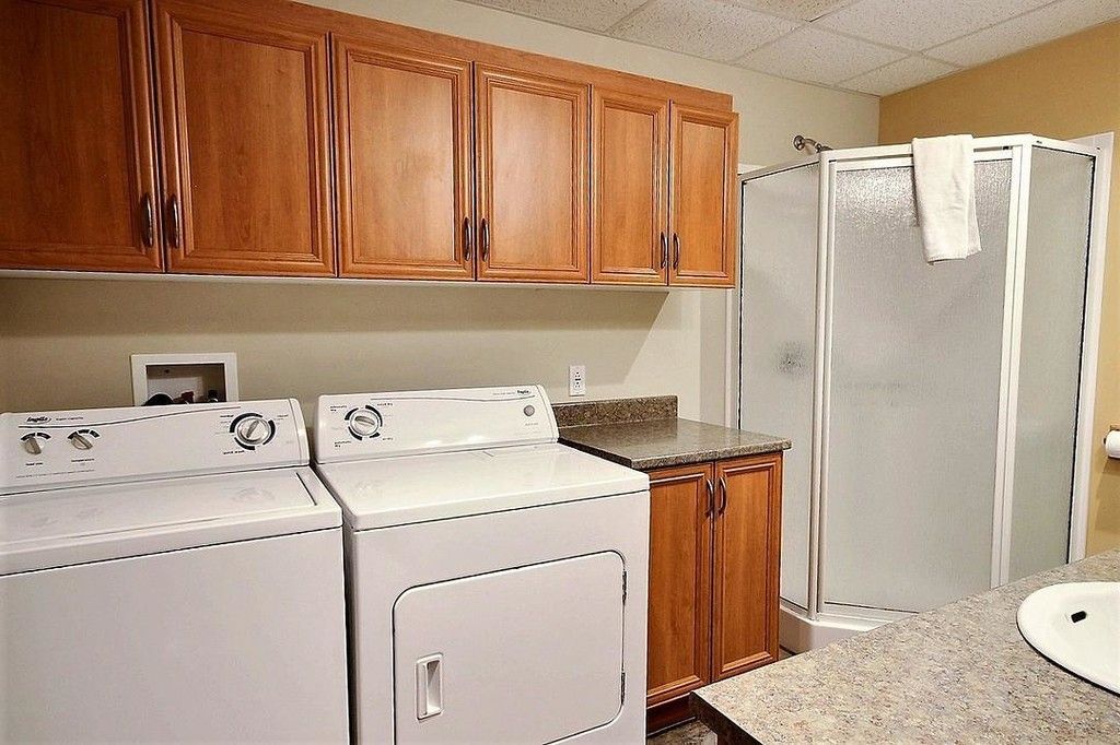 Laundry room with washer, dryer, cabinets, a shower, and countertop.
