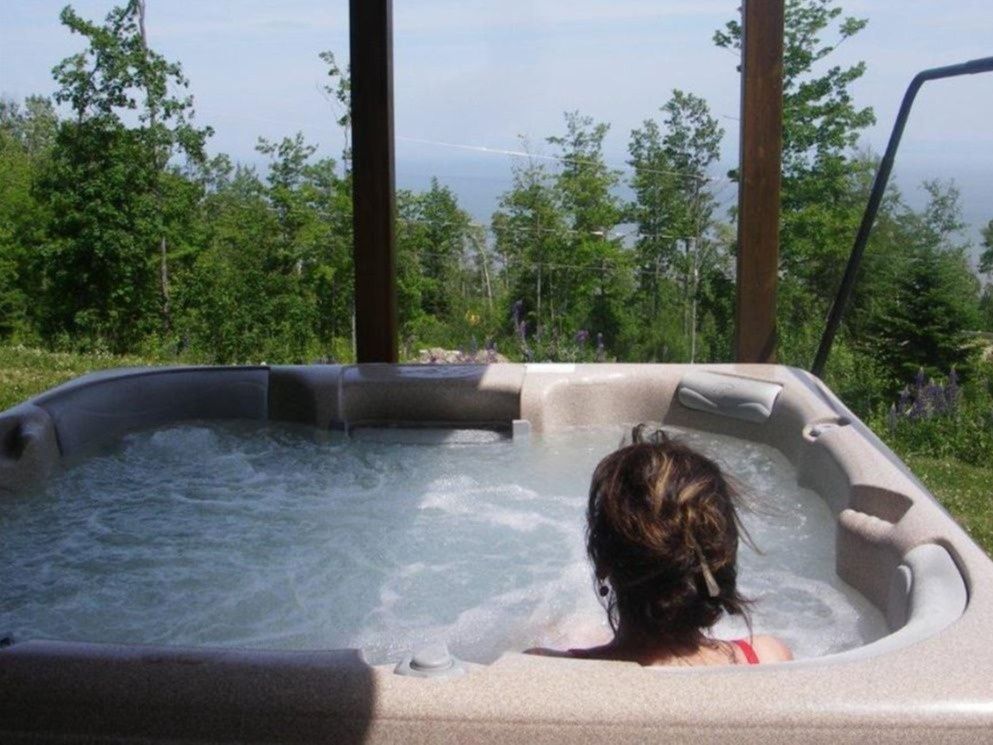 Person in a hot tub, trees and ocean view in the background. Bubbles in the water.