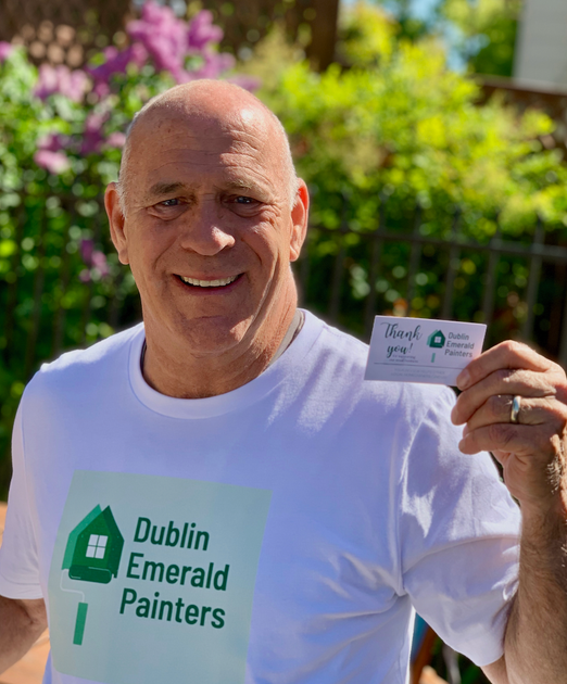 Man in white shirt smiling, holding business card for 