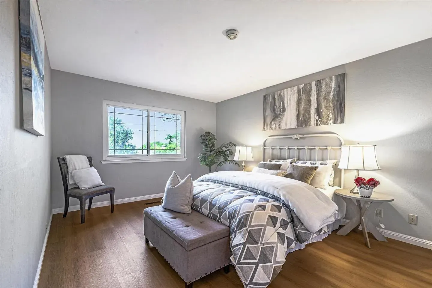 Bedroom with gray walls, wooden floor, window, bed, and decorative accents.