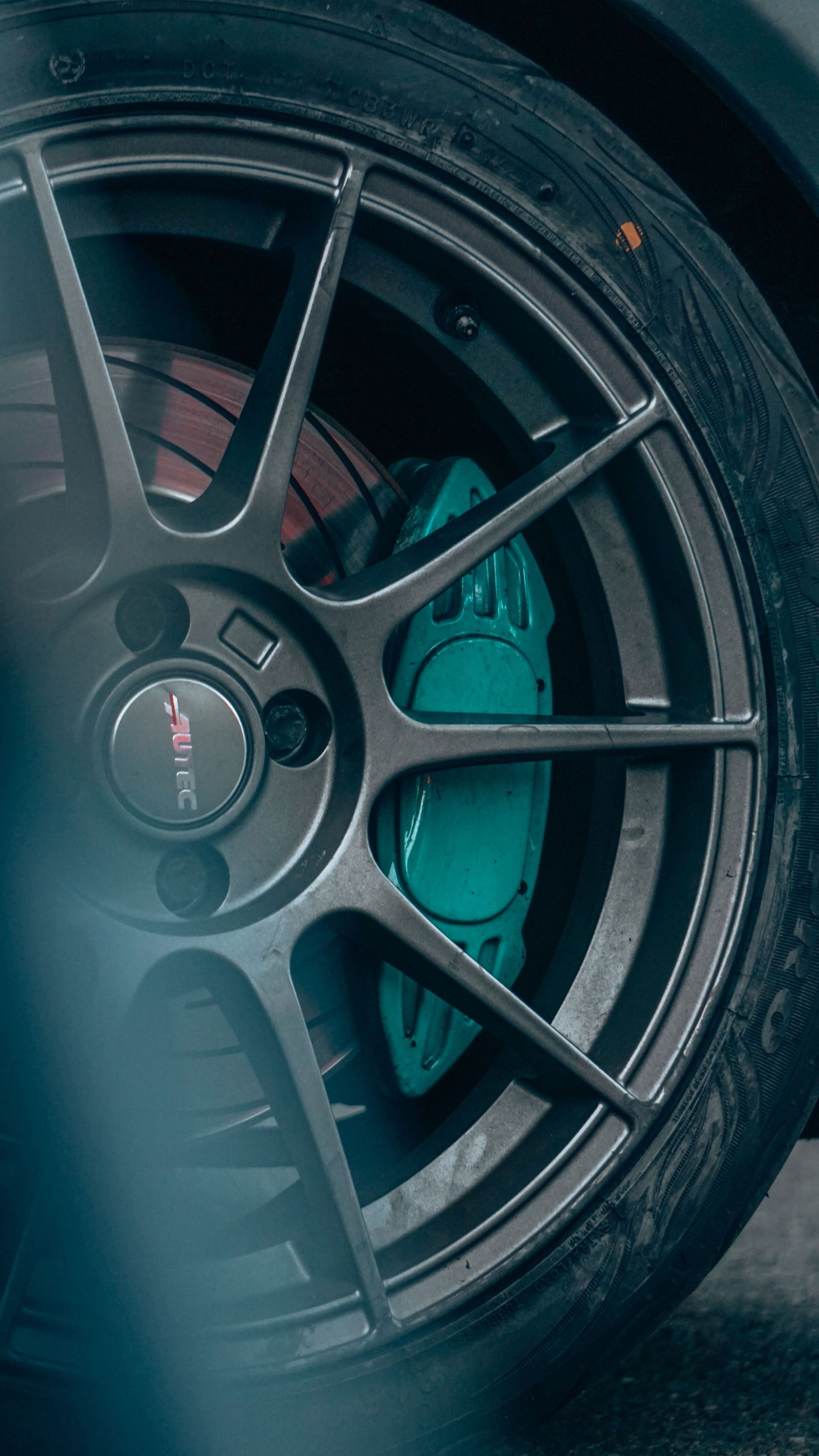 Close-up of a black sports car wheel with turquoise brake caliper